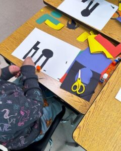Students working on this activity at their desks using paper, scissors, and glue sticks.